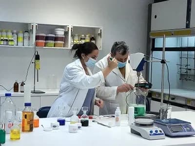 Dos técnicos con bata y mascarilla formulando una crema en un laboratorio de cosmética
